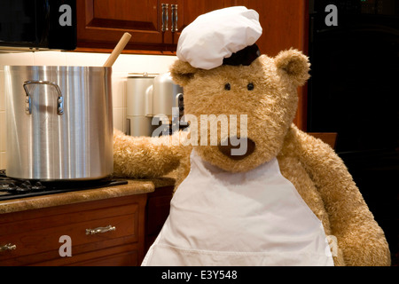 Überdimensionierte Teddybär gekleidet in Schürze und Hut des Küchenchefs in der Küche. Stockfoto