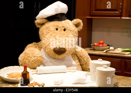 Überdimensionierte Teddybär gekleidet in Schürze und Hut des Küchenchefs in der Küche mit Nudelholz und Backen liefert. Stockfoto