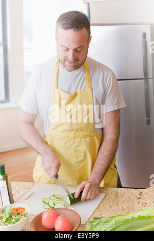 Reifer Mann bereitet frischen Salat in Küche Stockfoto