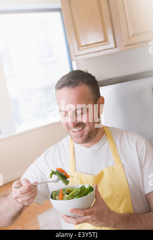 Reifer Mann Essen eine Schale mit frischem Salat in Küche Stockfoto