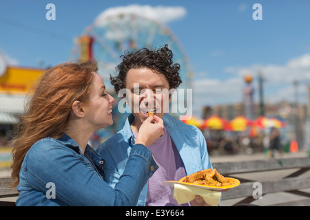 Romantisches Paar Fütterung einander Chips im Freizeitpark Stockfoto