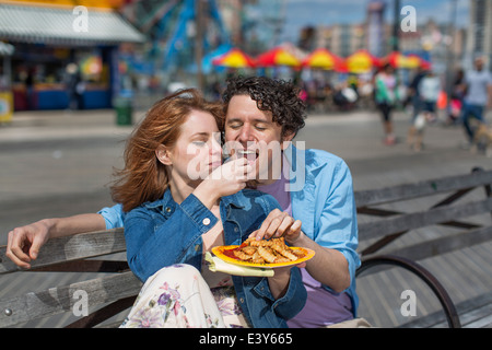 Romantisch zu zweit essen Chips im Freizeitpark Stockfoto