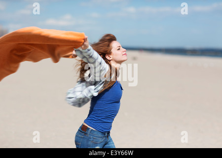 Junge Frau mit Decke auf windiger Strand Stockfoto