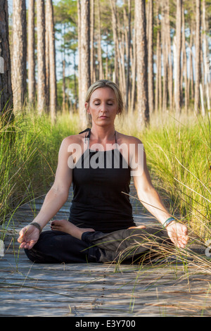Reife Frau praktizieren Yoga Meditation über Wald Gehweg Stockfoto