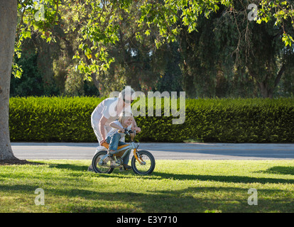 Drei Jahre alter Junge mit Großmutter im Park fahren lernen Stockfoto