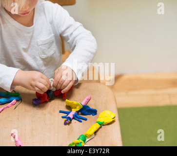 Aufnahme eines drei Jahre alten Jungen mit Knetmasse spielen beschnitten Stockfoto