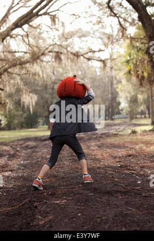 Junge in Wald festhalten Kürbiskopf laufen Stockfoto