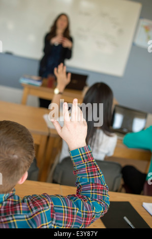 Student mit erhobenen Händen im Klassenzimmer Stockfoto