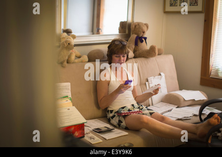 Mitte Erwachsene Frau sitzt auf dem Sofa, mit Handy Stockfoto