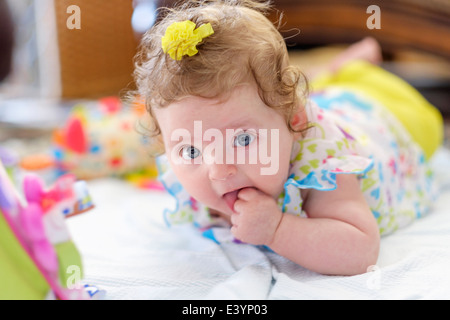 Ein drei Monate altes kaukasischen Kleinkind Mädchen, liegend auf Bauch kauen auf Faust. Stockfoto