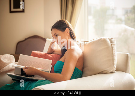 Junge Frau sitzt im Sessel Lesebuch Stockfoto