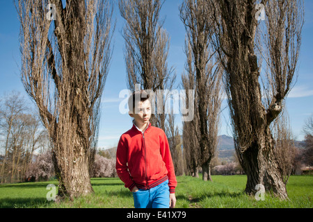 Zwölf Jahre alter Junge, von Bäumen gesäumten Feld spazieren Stockfoto