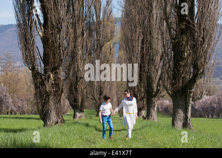 Zwölf Jahre alter Junge und Reife Mutter spazieren, von Bäumen gesäumten Feld Stockfoto