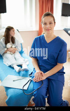 Krankenschwester, sitzen am Ende des Patientenbett Stockfoto