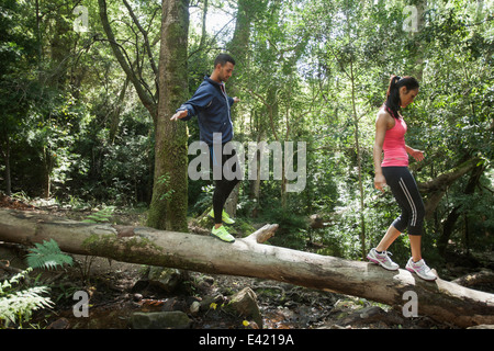 Junge Jogger balancieren auf Baumstamm Stockfoto