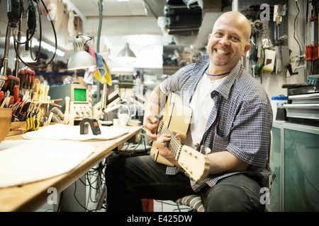 Porträt von Gitarrenbauer tuning Akustikgitarre in Werkstatt Stockfoto