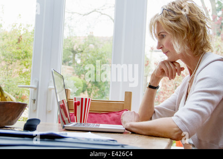 Reife Frau mit Laptop in der Küche Stockfoto