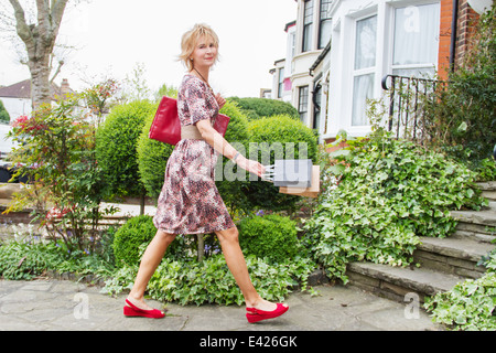 Reife Frau vor Haus mit Einkaufstüten Stockfoto