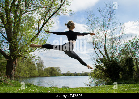 Junge Tänzerin, die Luft in der Nähe von See springen Stockfoto