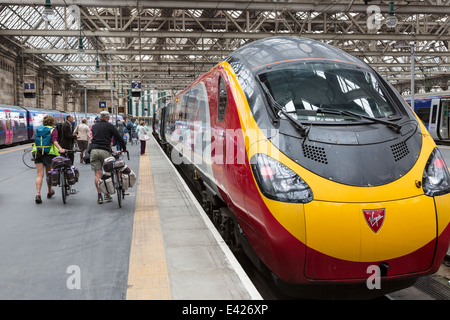 Zwei Radfahrer einsteigen in eine Jungfrau trainieren bei Glasgow Central Railway Station, Glasgow, Schottland, UK Stockfoto