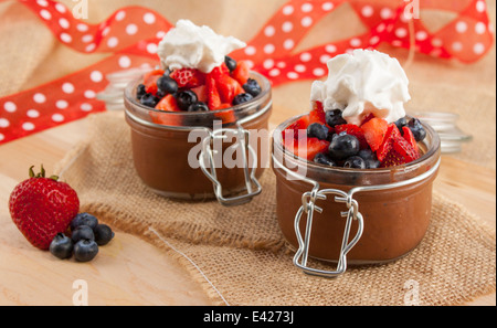 Mousse au Chocolat in niedlichen Container mit Heidelbeeren, Erdbeeren und Schlagsahne gekrönt. Vegan. Stockfoto