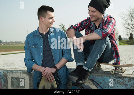 Junge Männer sitzen zusammen im skatepark Stockfoto