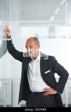 Geschäftsmann gegen reflektierenden Wand betrachten Stockfoto