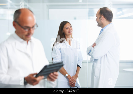 Männlichen Arzt mit digital-Tablette, Kolleginnen und Kollegen im Hintergrund Stockfoto