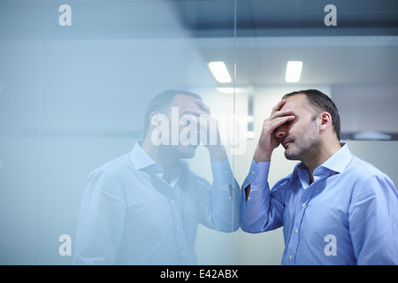 Mann verzweifelt vor reflektierenden Wand Stockfoto