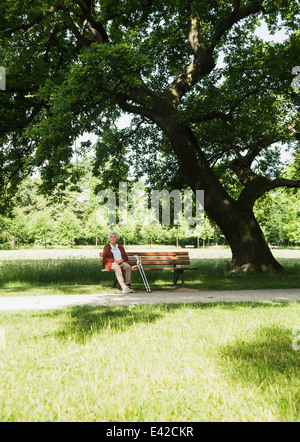 Ältere Frau sitzen auf der Parkbank im park Stockfoto