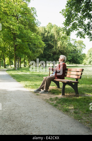 Ältere Frau sitzen auf der Parkbank im park Stockfoto