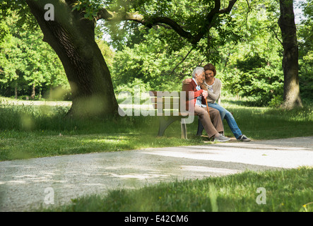 Ältere Frau sitzen auf der Parkbank mit Enkelin Stockfoto