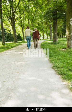 Ältere Frau und Enkelin zu Fuß durch den Park, mit Spazierstock Stockfoto