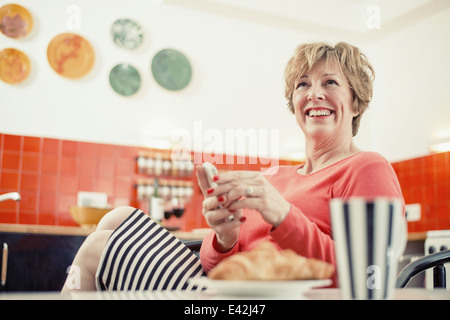 Reife Frau mit Handy in Küche, Porträt Stockfoto