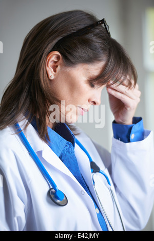 Arzt mit der Hand auf Kopf, Augen geschlossen Stockfoto