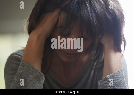 Reife Frau mit Kopf in Händen Stockfoto