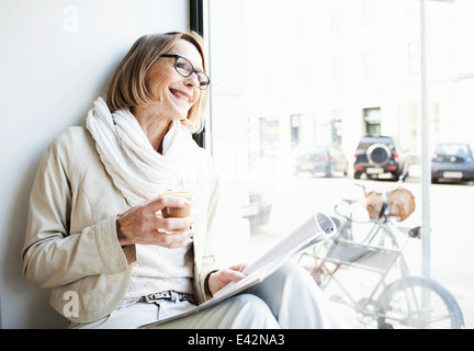 Ältere Frau mit einem Kaffee im Café Fensterplatz Stockfoto