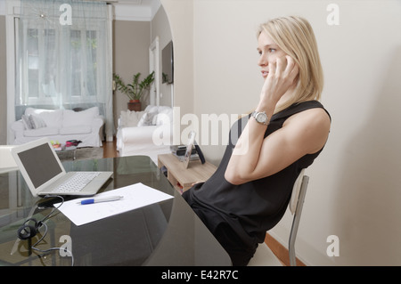 Junge Frau im Chat auf Smartphone zu Hause Schreibtisch Stockfoto