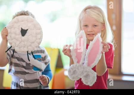 Jungen und Mädchen hält Schafe und Kaninchen Kreationen im Kindergarten Stockfoto
