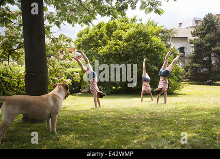 Mehreren zusammengesetzten jungen Frau Handstand im Garten zu tun Stockfoto