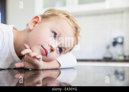 Porträt eines drei Jahre alten Jungen stützte sich auf Küchenbank Stockfoto