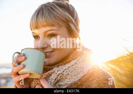 Porträt der jungen Frau im sonnendurchfluteten Marsh mit Getränke-Becher Stockfoto