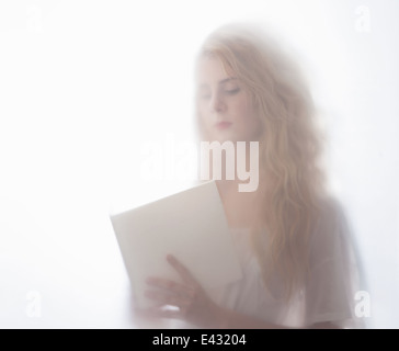 Verschwommene Aufnahme junge Frau Buch hinter Milchglas Stockfoto