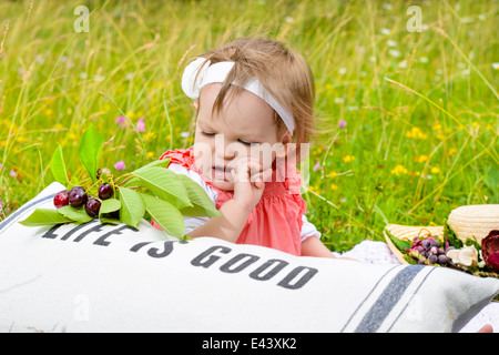 Niedliche Mädchen in der Natur schauen neugierig auf Kirschen Stockfoto