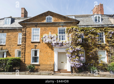 Traditionelles Cotswold Stadt Steinhaus in Shipston auf Stour, Warwickshire, mit lila Glyzinien wachsen rund um die Haustür Stockfoto