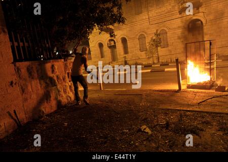 Bethlehem. 2. Juli 2014. Ein palästinensischer Demonstrant wirft Steinen auf israelische Soldaten bei Zusammenstößen in der Nähe von Rachels Grab in der West Bank Stadt Bethlehem am 2. Juli 2014. Die Entdeckung eines Körpers in Jerusalem Wald am Mittwoch erhöht Verdacht, dass eine fehlende palästinensischen Jugendlichen rächen den Tod von drei Israelis getötet worden war entführt jüdischen. Rock-werfende Palästinenser kollidierte mit israelischen Streitkräfte in Jerusalem und der Westbank nach den Nachrichten, aber keine ernsthaften Verletzungen wurden berichtet. Bildnachweis: Luay Sababa/Xinhua/Alamy Live-Nachrichten Stockfoto