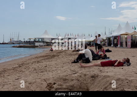 Strand mit Liegewiese Frau und Festival-Gänger bei den Filmfestspielen in Cannes, Frankreich. Stockfoto