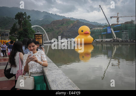 Guiyang, China Provinz Guizhou. 3. Juli 2014. Ein Bewohner posiert für Fotos mit eine riesige gelbe Gummiente schwimmend auf Nanming Fluss in Guiyang, Hauptstadt der Südwesten Chinas Provinz Guizhou, 3. Juli 2014. Die 18-Meter-hohen Gummiente Geistesprodukt des holländischen Künstlers Florentijn Hofman, wird in Guiyang vom 4. Juli 24. August Liegeplatz. Bildnachweis: Ou Dongqu/Xinhua/Alamy Live-Nachrichten Stockfoto