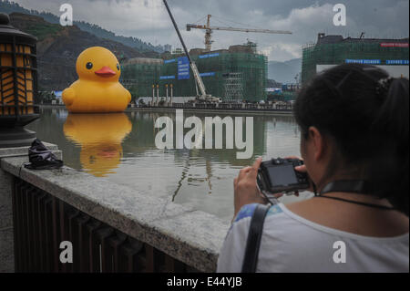 Guiyang, China Provinz Guizhou. 3. Juli 2014. Ein Bewohner nimmt Foto eine riesige gelbe Gummiente schwimmend auf Nanming Fluss in Guiyang, Hauptstadt der Südwesten Chinas Provinz Guizhou, 3. Juli 2014. Die 18-Meter-hohen Gummiente Geistesprodukt des holländischen Künstlers Florentijn Hofman, wird in Guiyang vom 4. Juli 24. August Liegeplatz. Bildnachweis: Ou Dongqu/Xinhua/Alamy Live-Nachrichten Stockfoto