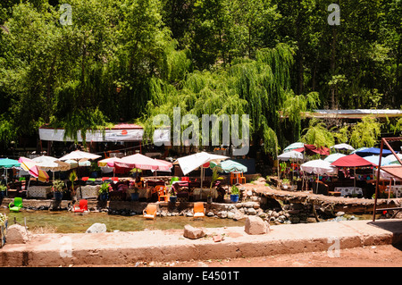 Kunststoff Terrasse Tische, Stühle und Sonnenschirme in den Restaurants am Ufer des Flusses Ourika, Ourika Valley, Atlas, Marokko Stockfoto